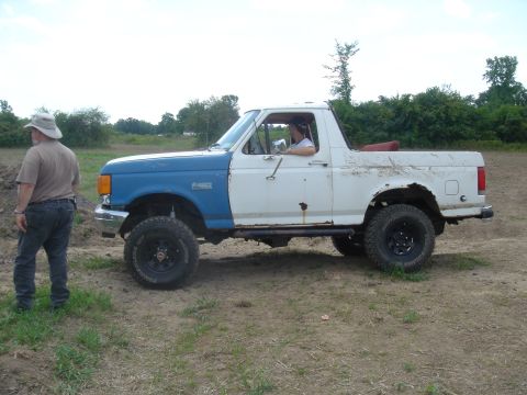 1979 Ford F-250 - A man stands next to a lifted Ford Bronco with mismatched front fenders.