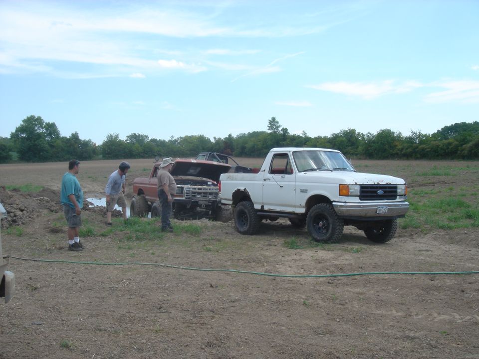 White Ford pickup truck with black rims, mud tires, and a lifted suspension