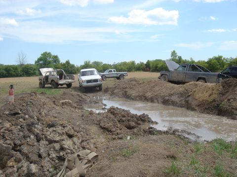 1979 Ford F-250 - Off-road trucks navigate a challenging muddy terrain on a sunny day.