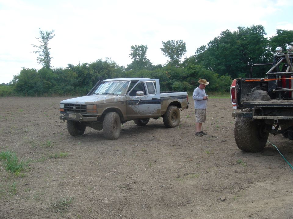 Muddy pickup truck with snorkel and off-road tires, parked in a field
