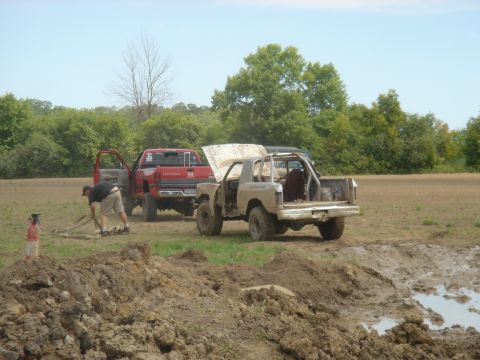 1979 Ford F-250 - Two off-road vehicles are stuck in the mud, with one person attempting to free them.