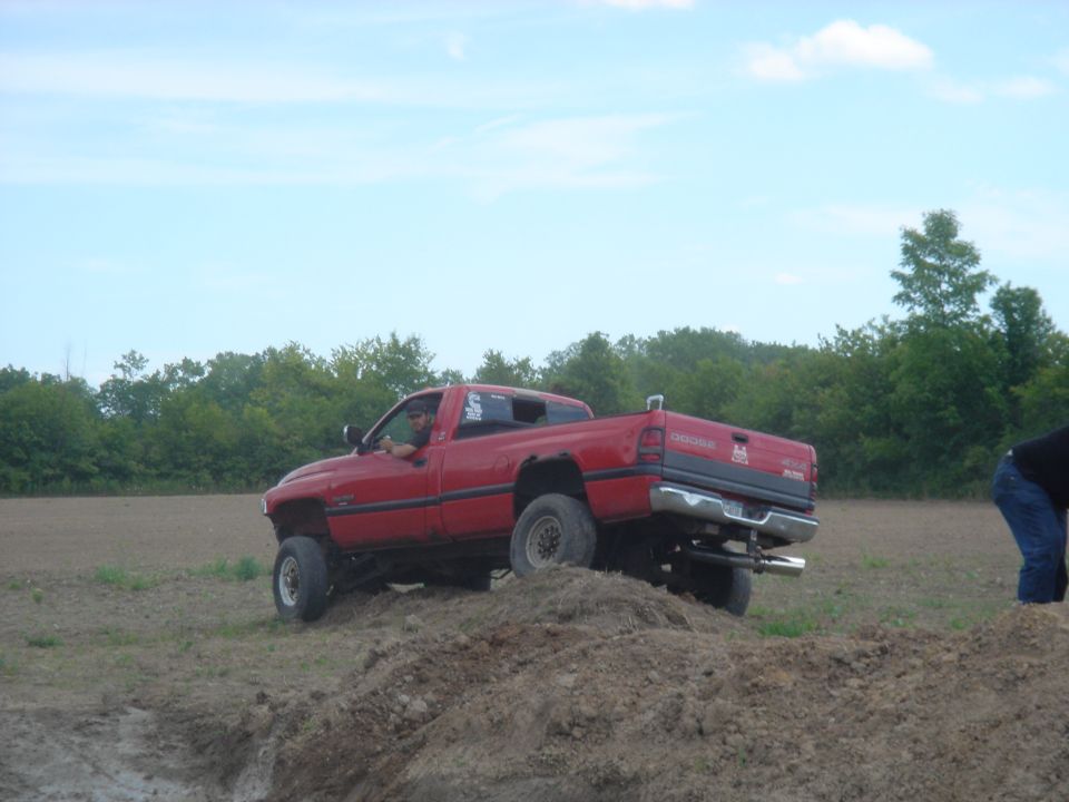 Red pickup truck with lifted suspension driving on a dirt mound