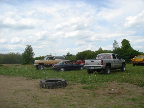 1979 Ford F-250 - Several vehicles are parked in a grassy area under a cloudy sky.