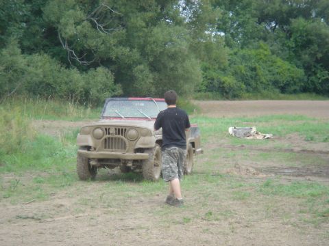 1979 Ford F-250 - A muddy Jeep CJ-5 is seen from the front in an outdoor, grassy area.