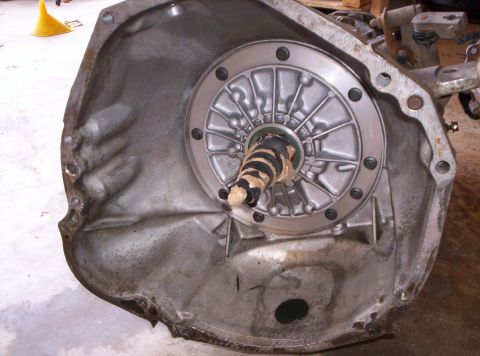 1995 Ford Bronco - Bellhousing face of an automatic transmission lying on a shop floor, looking straight into the torque converter with its ribbed cover, moun…