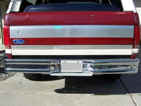1991 Ford Bronco - The rear of a 1991 Ford Bronco, showing its chrome bumper and distinctive red and silver tailgate panel.