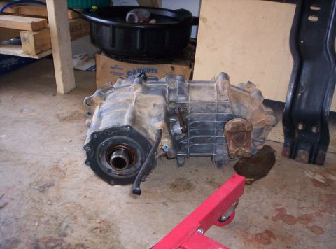 1995 Ford Bronco - Transfer case assembly shown on a concrete floor, with a red engine stand visible.