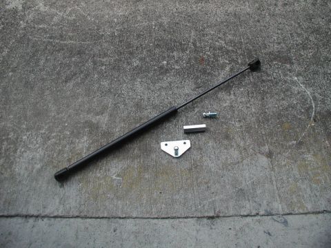 1990 Ford Thunderbird - A trunk strut with its associated mounting hardware is displayed on a concrete surface.