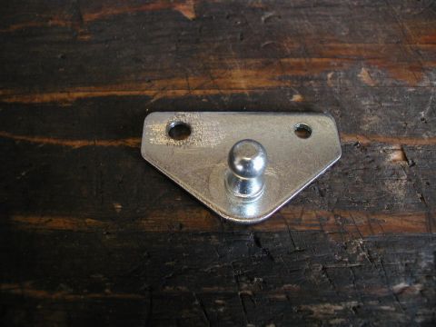 1990 Ford Thunderbird - A metal bracket with a ball stud, likely for a trunk strut, is shown against a dark wooden background.