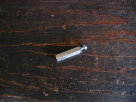 1990 Ford Thunderbird - A single trunk strut ball stud rests on a weathered wooden surface.