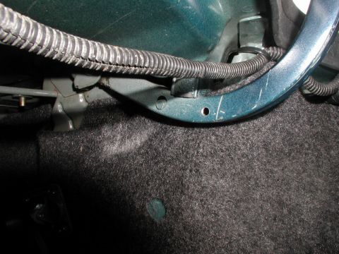 1990 Ford Thunderbird - Close-up of a vehicle's trunk strut assembly, showing metal components and carpet lining.