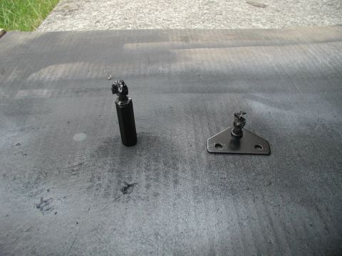 1990 Ford Thunderbird - Two black metal trunk strut components are shown on a dark, textured surface.