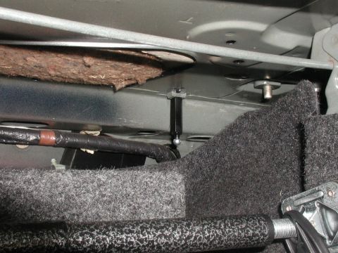 1990 Ford Thunderbird - Close-up view of a vehicle's trunk strut assembly, showing mechanical components and interior lining.