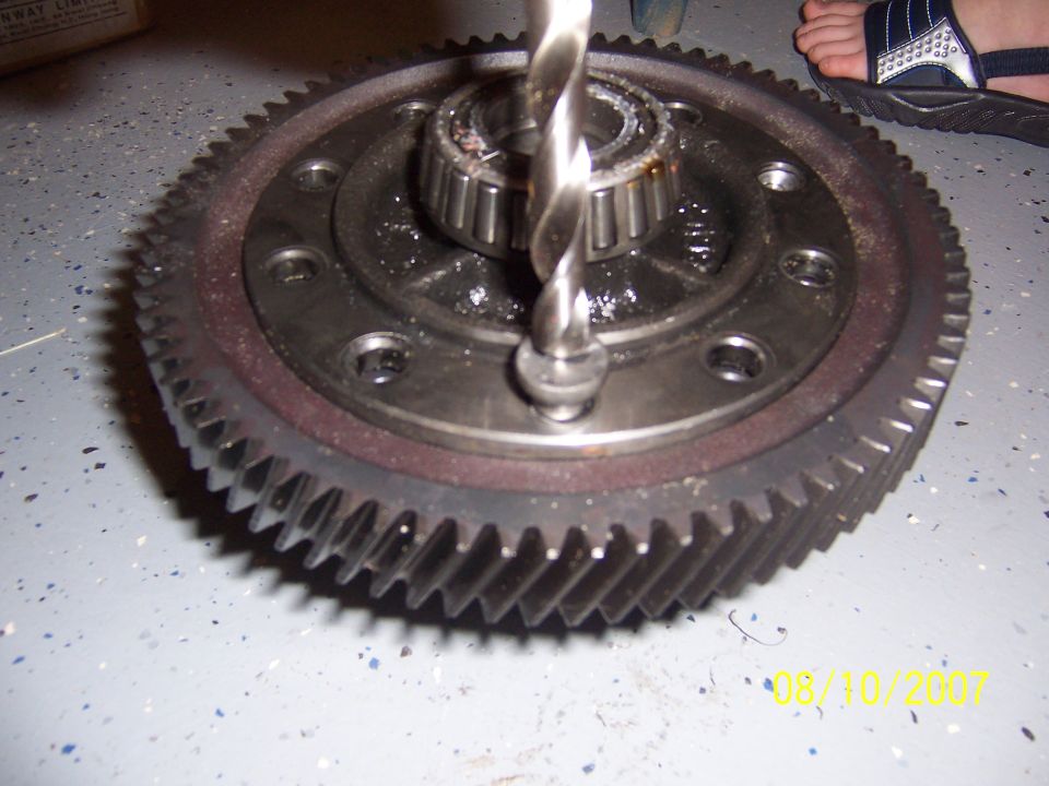 Person drilling a transmission gear on a bench