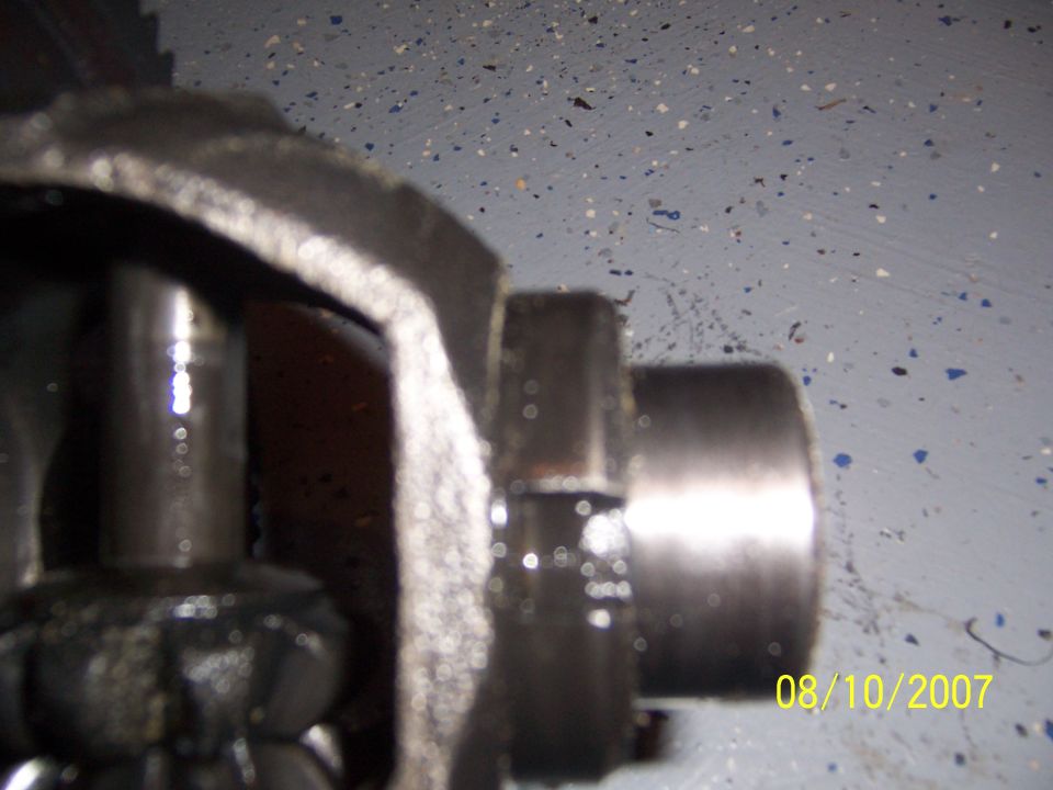 Blurry close-up of a machined driveshaft stub and cast metal yoke on a gray speckled floor, dated 08/10/2007