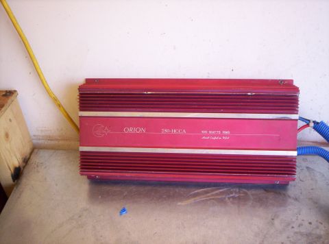 1995 Ford Bronco - A red Orion 250-HCCA car audio amplifier rated 100 watts RMS, marked "Hand Crafted in USA", sitting upright on a concrete floor against a w…