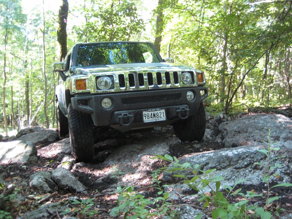 Hummer H3 on rocky terrain, front view. Chrome grille, black bumper, license plate 984M821