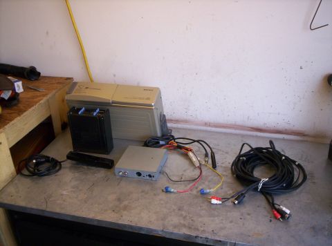 1995 Ford Bronco - A disassembled Sony 10-disc CD changer car audio setup laid out on a steel workbench: the silver changer unit, a black disc magazine, a sma…