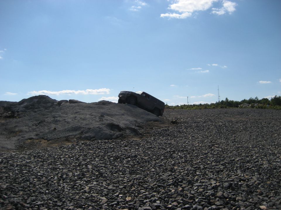 Dark SUV tilted on a rocky incline under a blue sky