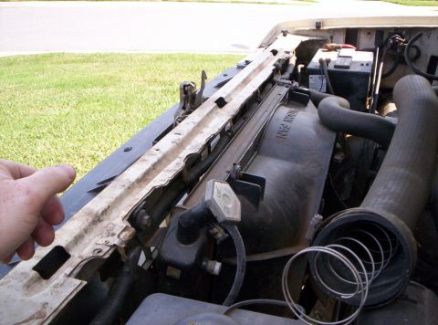 1995 Ford Bronco - View across the front core support of a white Ford truck with the hood open, showing the radiator top tank marked 'HEAVY DUTY', its hex cap…