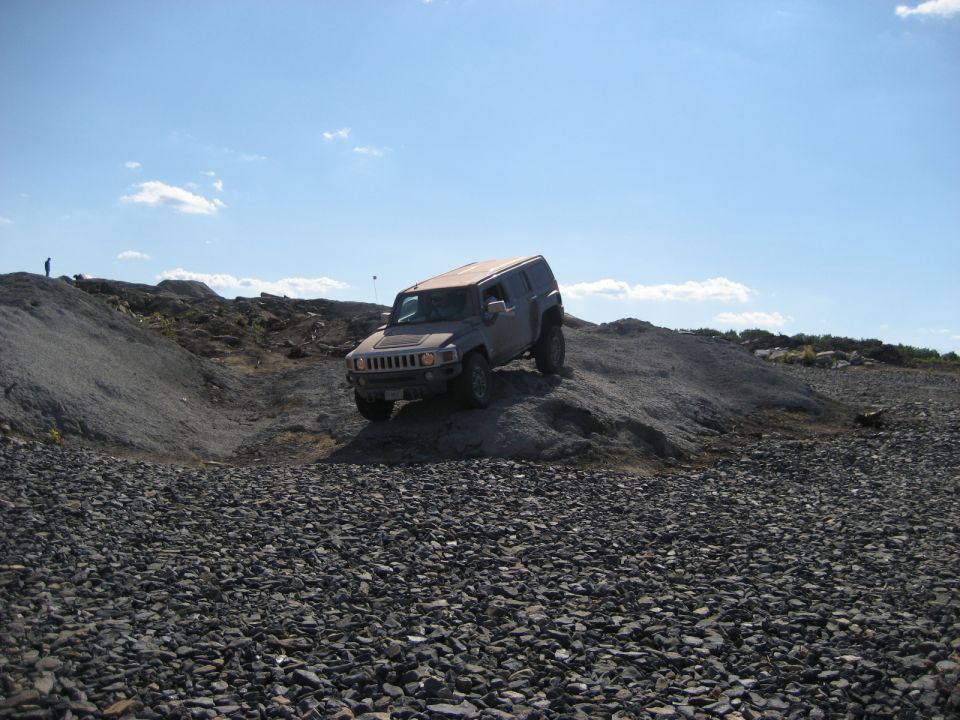 Hummer H3 driving on a rocky incline under a blue sky