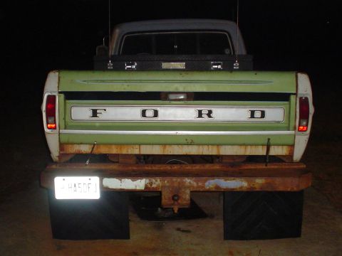 1967 Ford F-250 - Rear view of a green and white Ford pickup truck, showing the tailgate and rusty bumper.