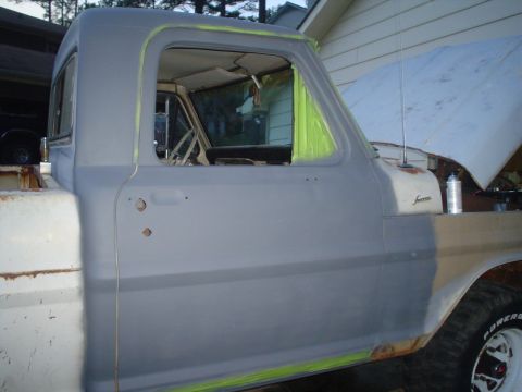 1967 Ford F-250 - A primer-coated 1967 Ford F-250 truck is undergoing bodywork, with the hood open and the driver's side door visible.