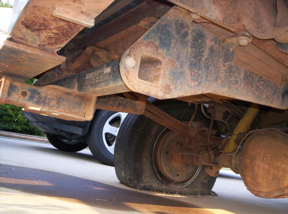Rusted truck frame underside showing leaf springs, rear axle and differential