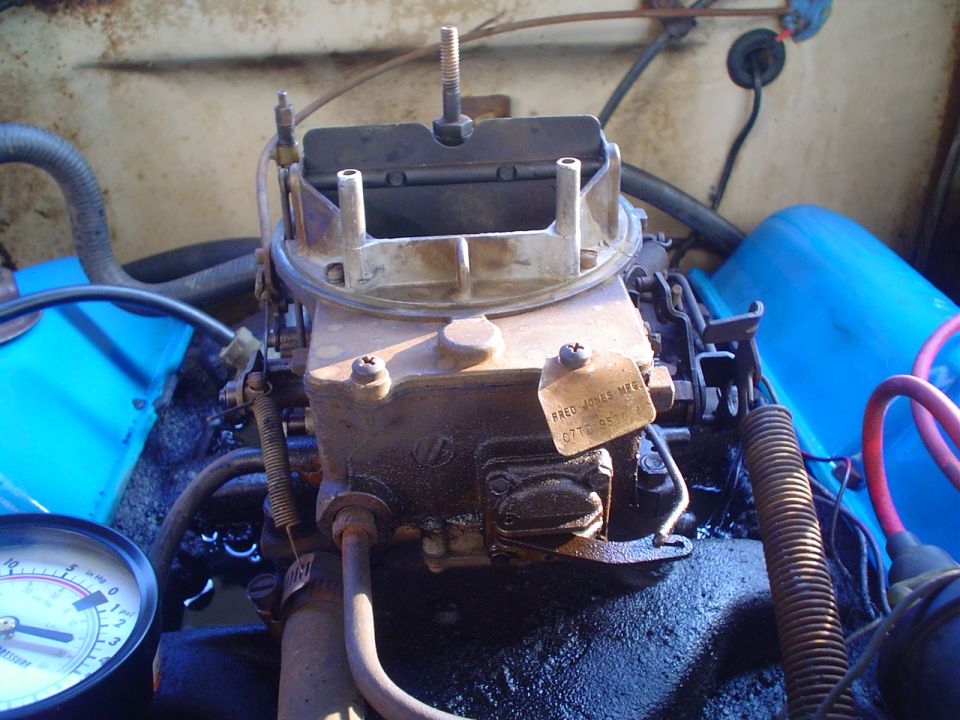 Close-up of a carburetor with a pressure gauge attached