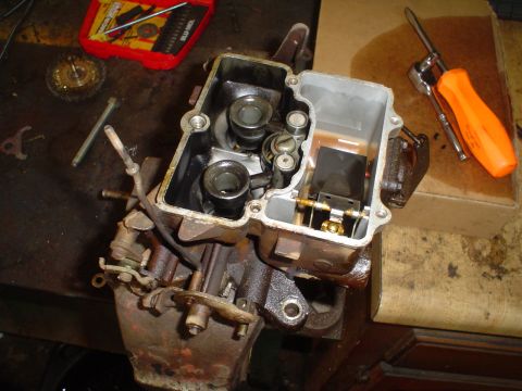 1967 Ford F-250 - A disassembled carburetor sits on a workbench next to tools, including a screwdriver and a socket wrench.