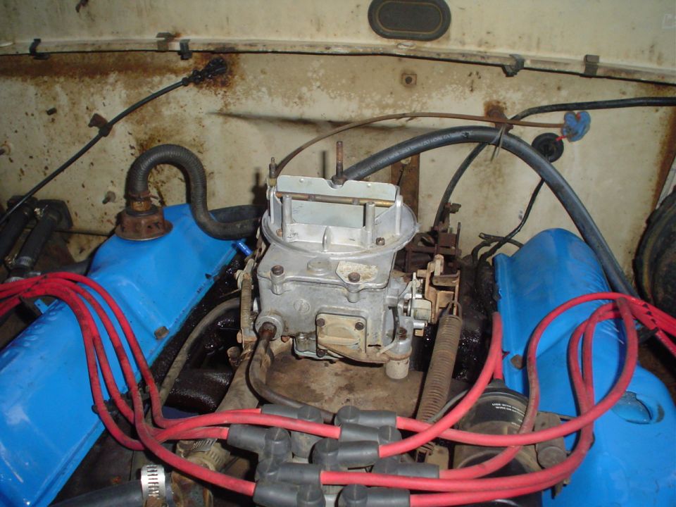 Close-up of a V8 engine's carburetor, intake manifold, and spark plug wires
