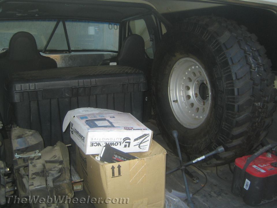Spare off-road tire on a steel wheel and a battery loaded behind vehicle seats