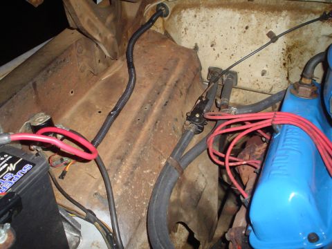 1967 Ford F-250 - Close-up view of an engine bay, showing a blue valve cover, red spark plug wires, and battery connections.