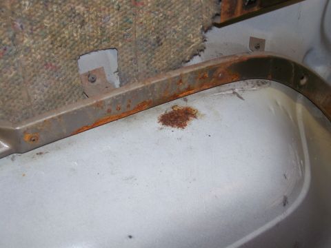 1986 Ford Bronco - Interior view of rusted metal trim and carpet backing, likely from a vehicle's floor.