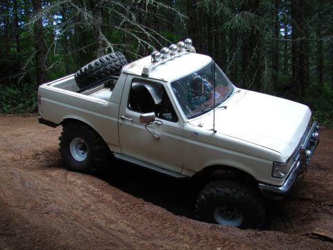 1996 Ford Bronco - This lifted 1996 Ford Bronco is shown tackling a challenging off-road trail with large, aggressive tires.