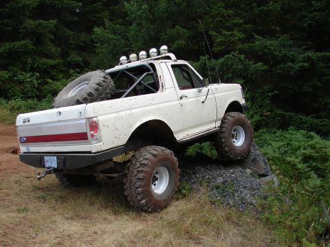 1996 Ford Bronco - This modified white Ford Bronco is shown off-roading on a rocky incline.