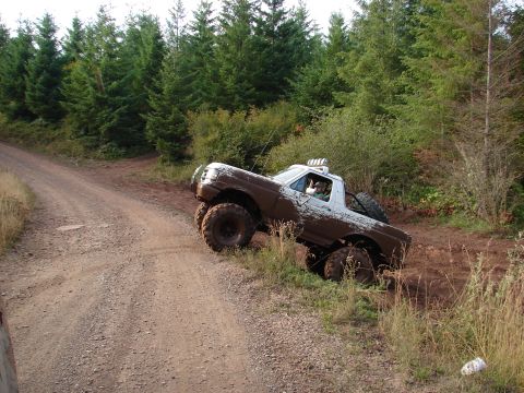 1996 Ford Bronco - Muddy 1996 Ford Bronco navigating a dirt trail through a wooded area.