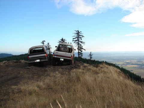 1996 Ford Bronco - Two 1996 Ford Broncos are parked on a grassy hill, offering a scenic view of the valley below.