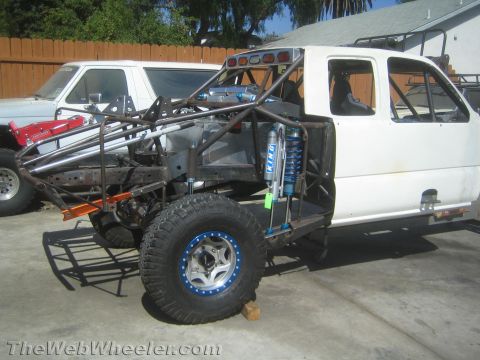 1990 Ford Bronco - white-cab off-road prerunner truck built on a tube chassis with a King coilover shock and beadlock wheel, in a driveway.