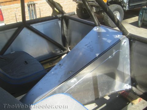 1990 Ford Bronco - Interior of an off-road buggy showing roll-cage tubing, a blue-trimmed bucket seat and bare aluminum panels.