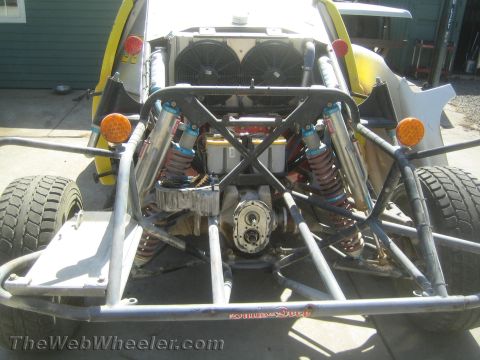 1990 Ford Bronco - Rear of a tube-frame off-road buggy showing twin coilover shocks, dual radiator fans and an exposed differential.