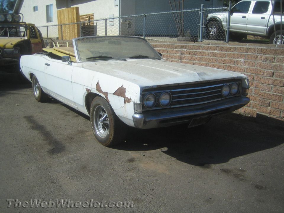 Weathered white late-1960s convertible with quad headlights and peeling paint