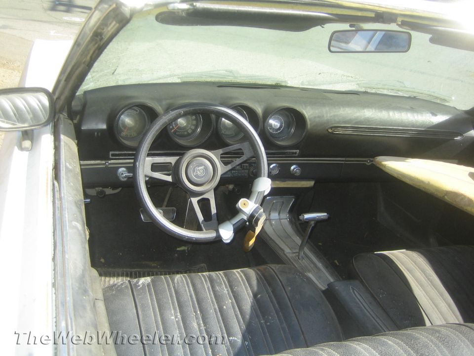 Interior of vintage convertible with three-spoke steering wheel and round gauges