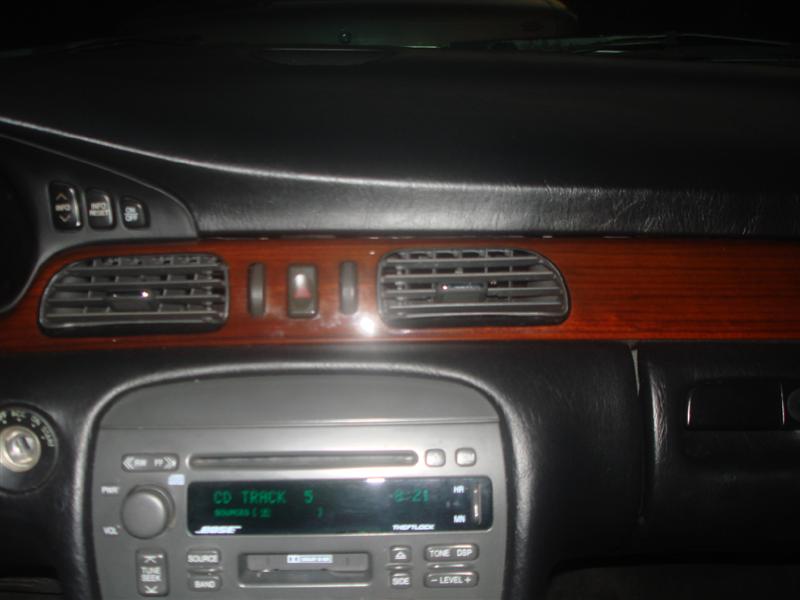 Cadillac interior dash with Bose radio showing CD Track 5 and wood-grain trim