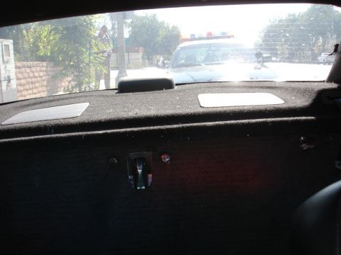 1993 Ford Taurus - A police car is visible through the rear window of another vehicle, with a person standing on the sidewalk.