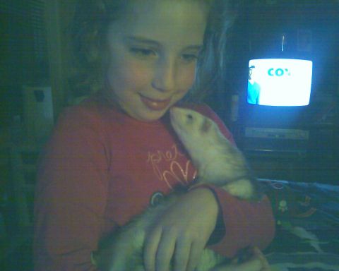 1993 Ford Bronco - A young girl cuddles a ferret while a television displays a bright screen in the background.