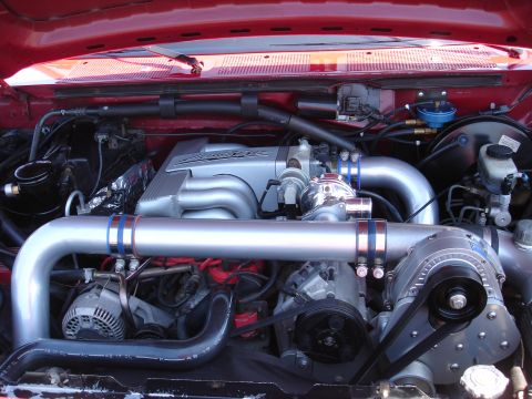 1993 Ford Taurus - Close-up view of a modified engine bay a supercharger and custom intake plumbing.