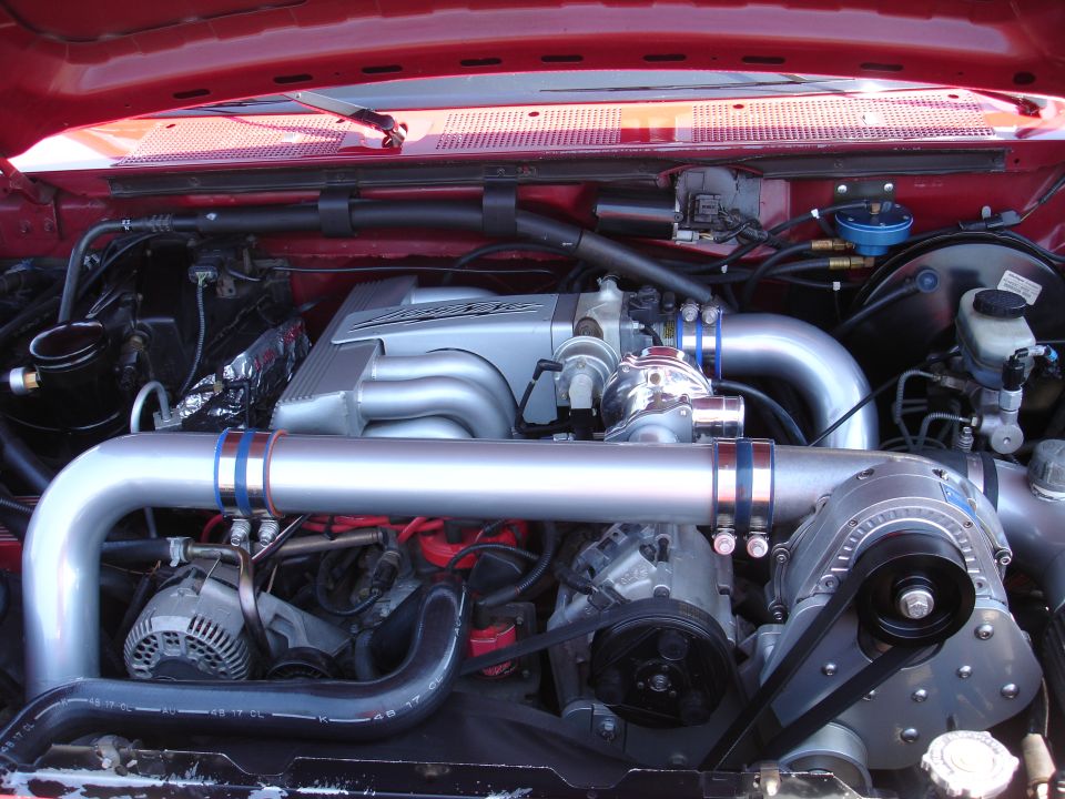 Engine bay with a prominent supercharger and silver intake manifold
