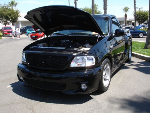 1993 Ford Taurus - Black 1999 Ford F-150 Lightning pickup truck parked outdoors with hood open.