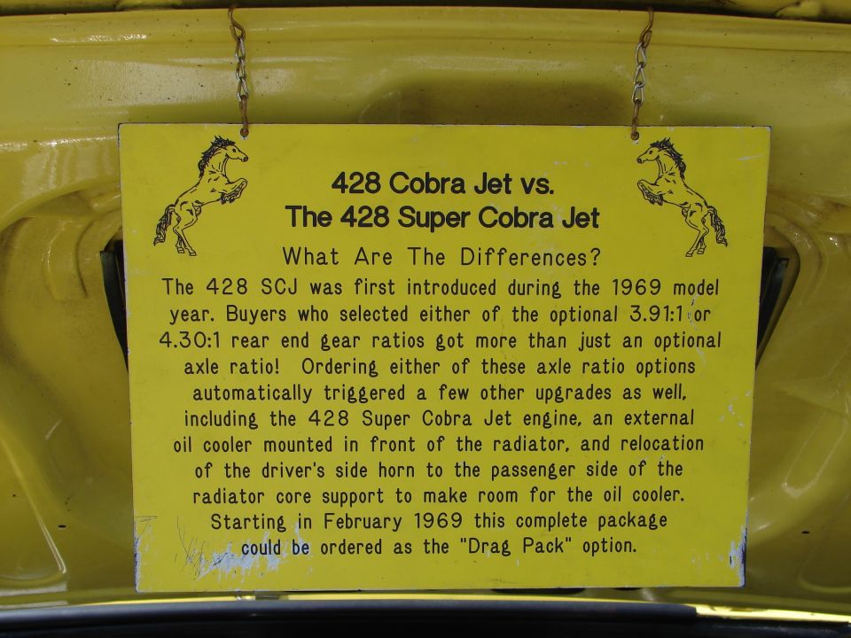 Yellow sign detailing differences between 428 Cobra Jet and 428 Super Cobra Jet engines, with horse graphics